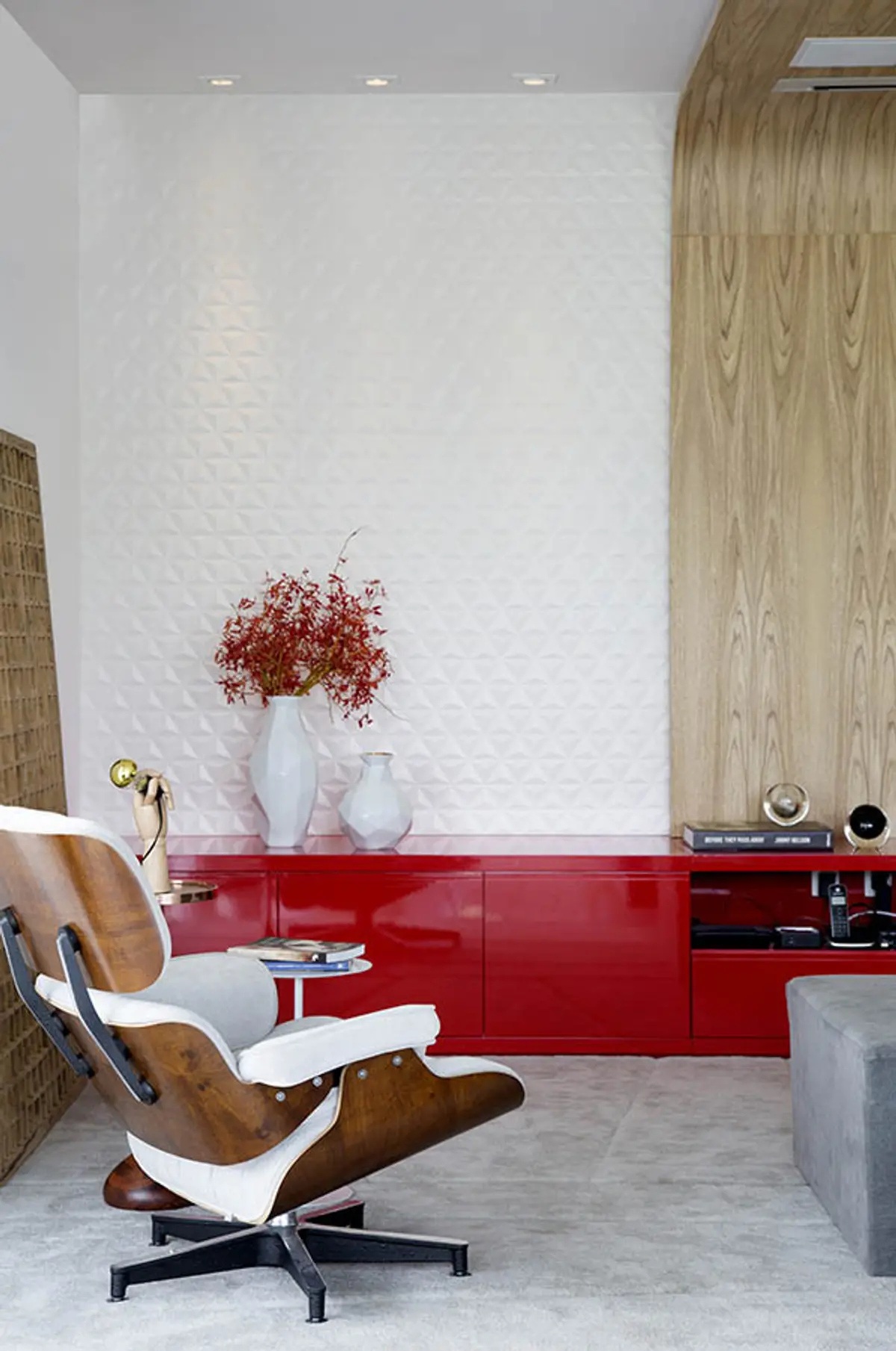 Living moderno con mueble rojo, sillón eames y pared textil blanca — proyecto Casa Blue House, por Amanda Miranda