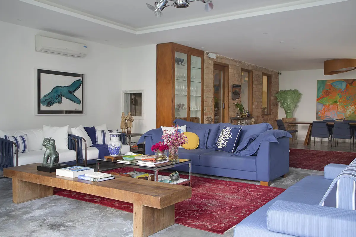 Living contemporáneo con sofá azul, mesa de madera y muebles de exposición — proyecto Casa Jardim Guanabara, por Amanda Miranda