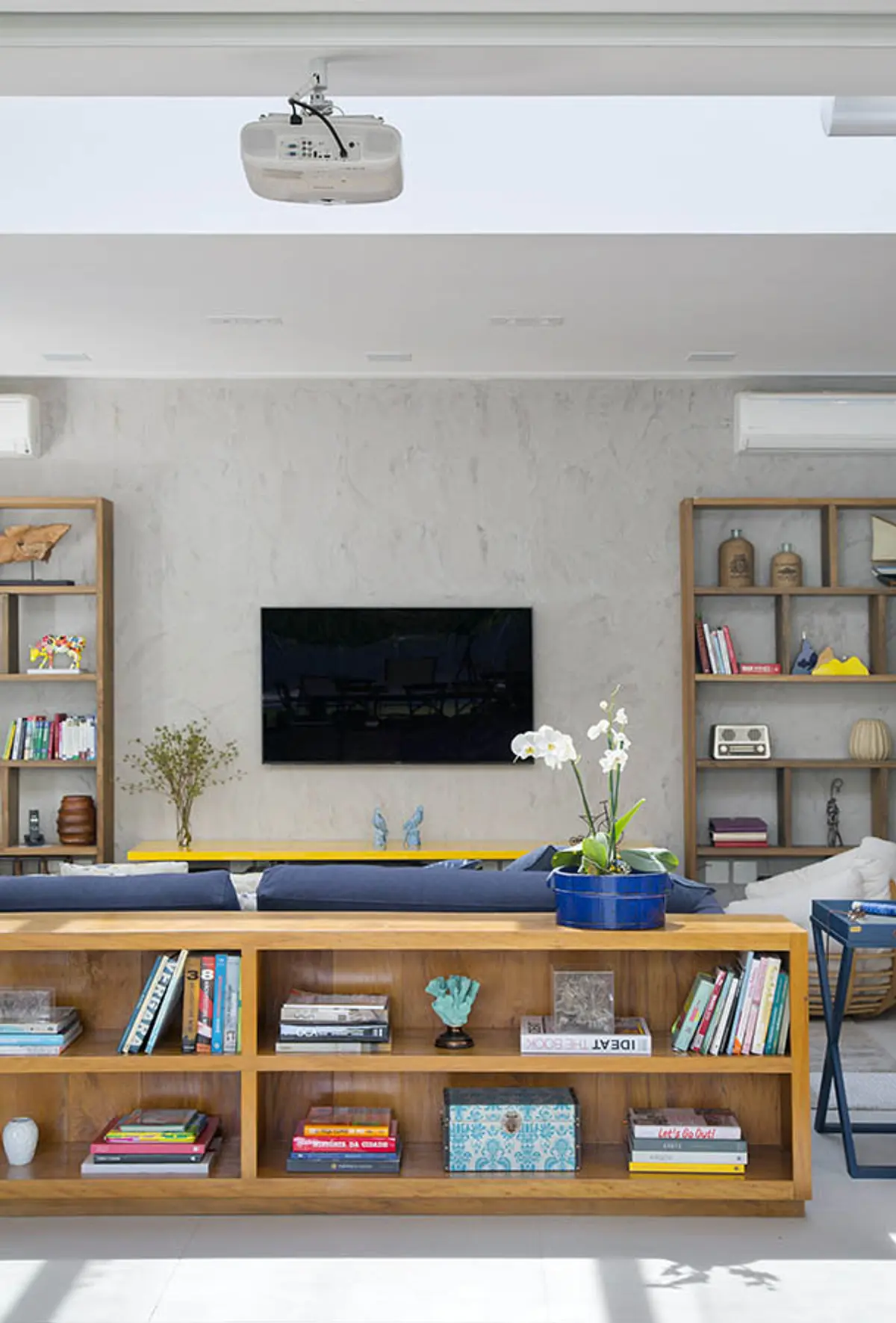 Living moderno con estanterías integradas y pared texturizada — proyecto Casa Jardim Ubá, por Amanda Miranda