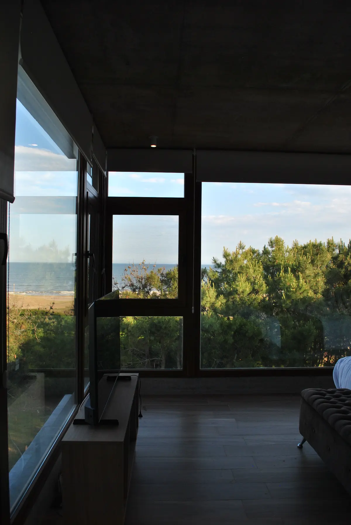 Sala moderna con vista al mar y grandes ventanales — proyecto Casa FSC, por TAVA Coop, en Pinamar