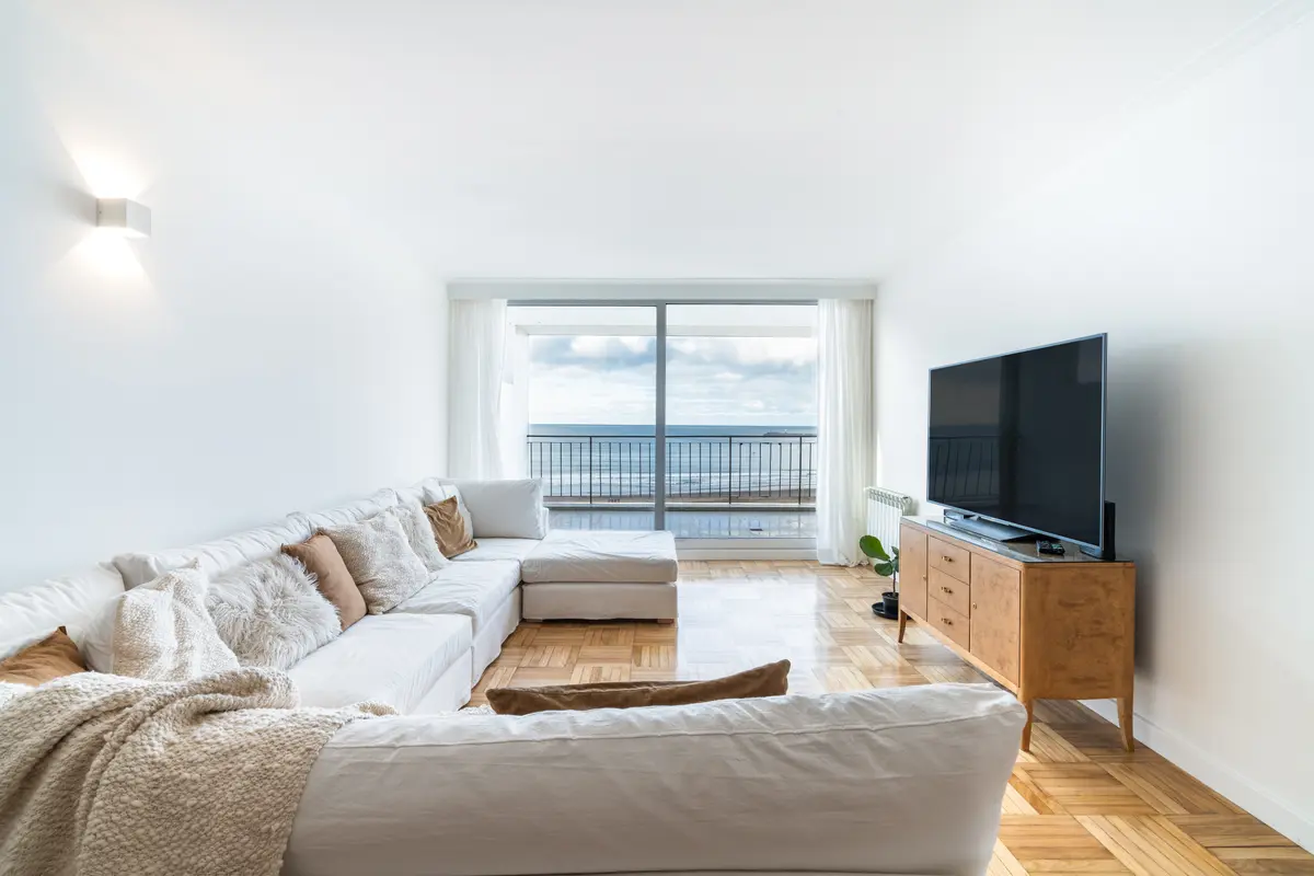 Sala moderna com vista para o mar e sofá branco — projeto TERRAZA PALACE, por Maria Menna Arquitecta, em Mar del Plata