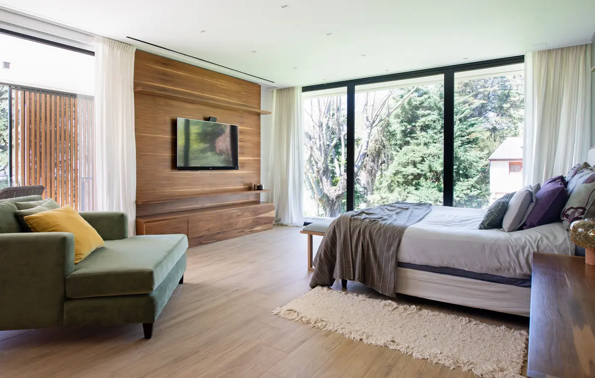 Dormitorio moderno con living integrado y vistas al bosque — proyecto Casa Highland Park, por C - ESTUDIO, en Pilar