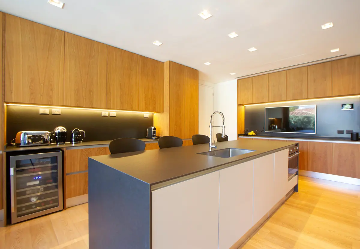 Cozinha moderna com ilha, armários de madeira e eletrodomésticos embutidos — projeto CASA BPO, por radovic_arquitecto, em San Isidro