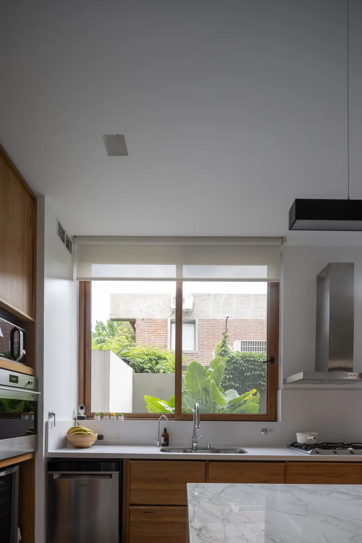 Cocina moderna con ventanales amplios y madera natural — proyecto CASA OrAz, por Alfredo Orfila arquitectura, en San Isidro