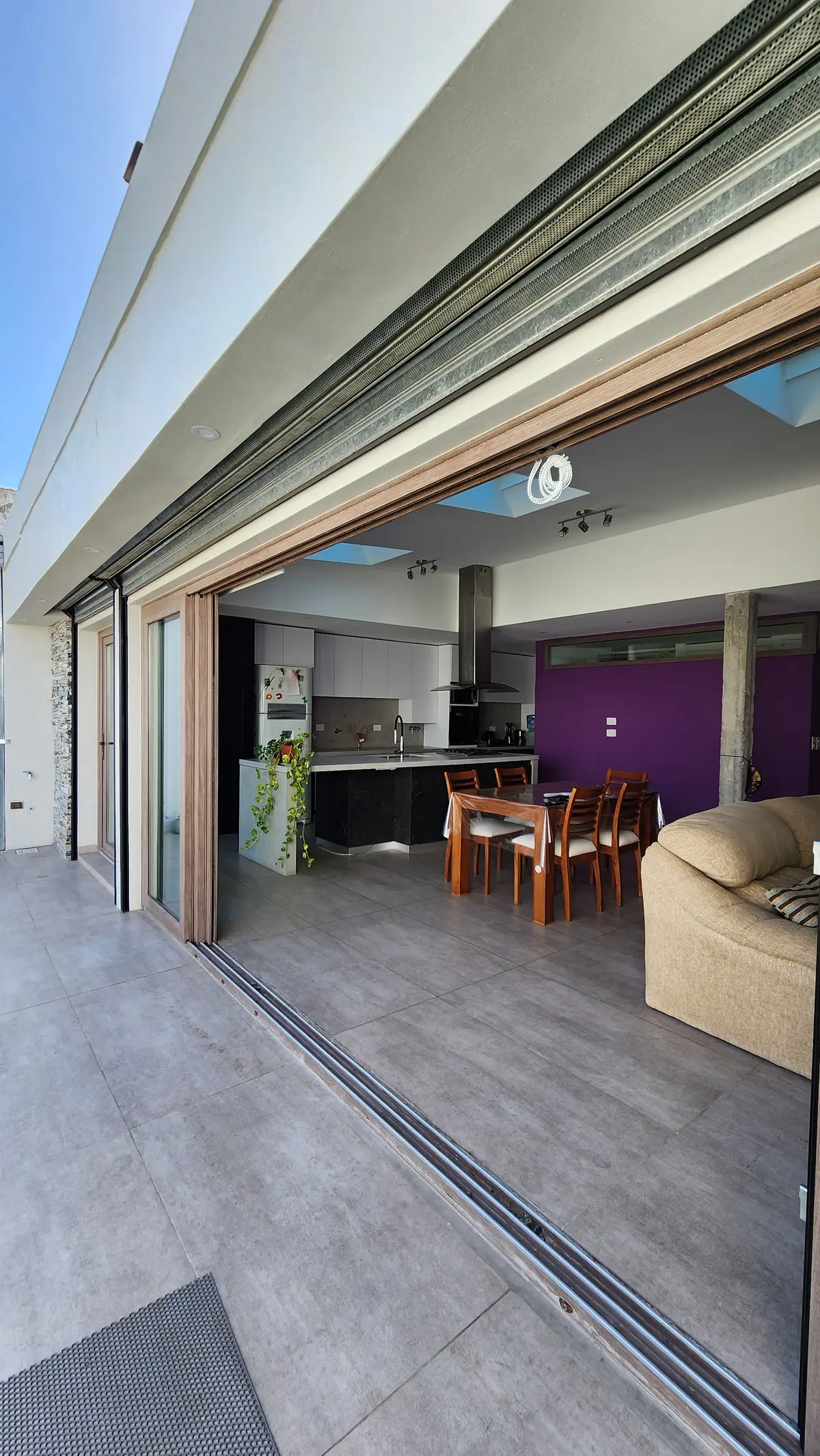 Cocina moderna abierta con comedor y sala, patio con puertas corredizas y vegetación — proyecto Casa Berner, por Zima Arquitectura, en La Plata