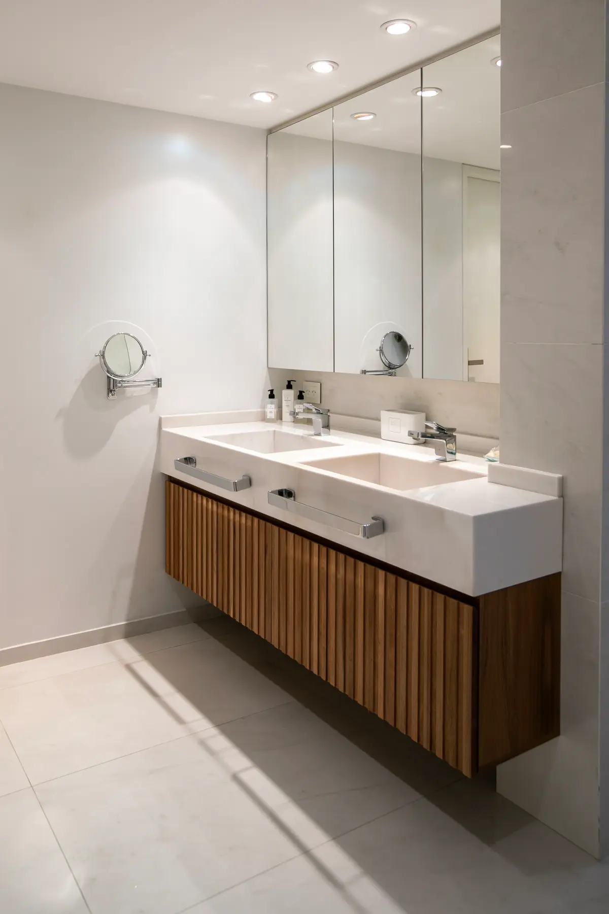 Baño moderno con vanitory de madera acanalada, doble bacha y espejo redondo — proyecto Obra Montevideo, por Arq. Lourdes Yarade Saravia, en Buenos Aires