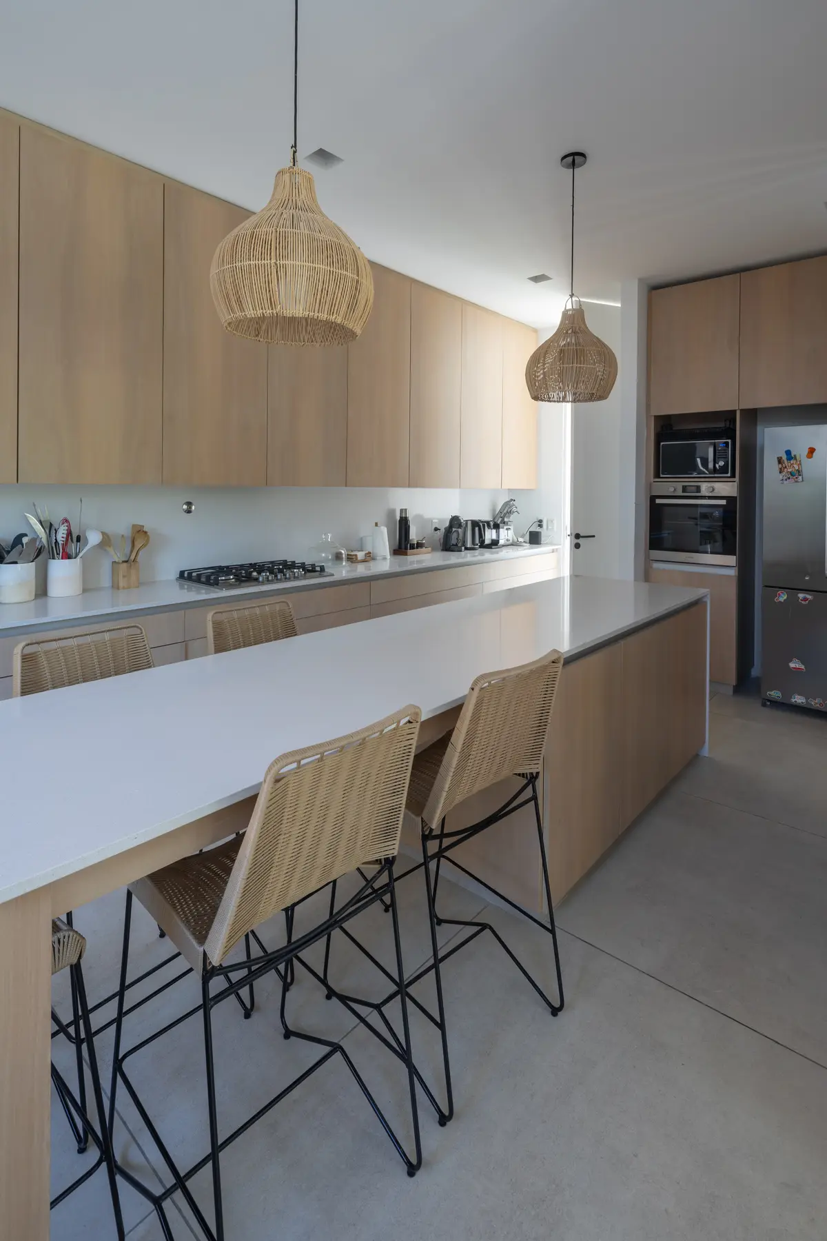 Cocina moderna con isla de madera, iluminación cálida y muebles de estilo escandinavo — proyecto CASA BaCa, por Alfredo Orfila arquitectura, en Benavidez