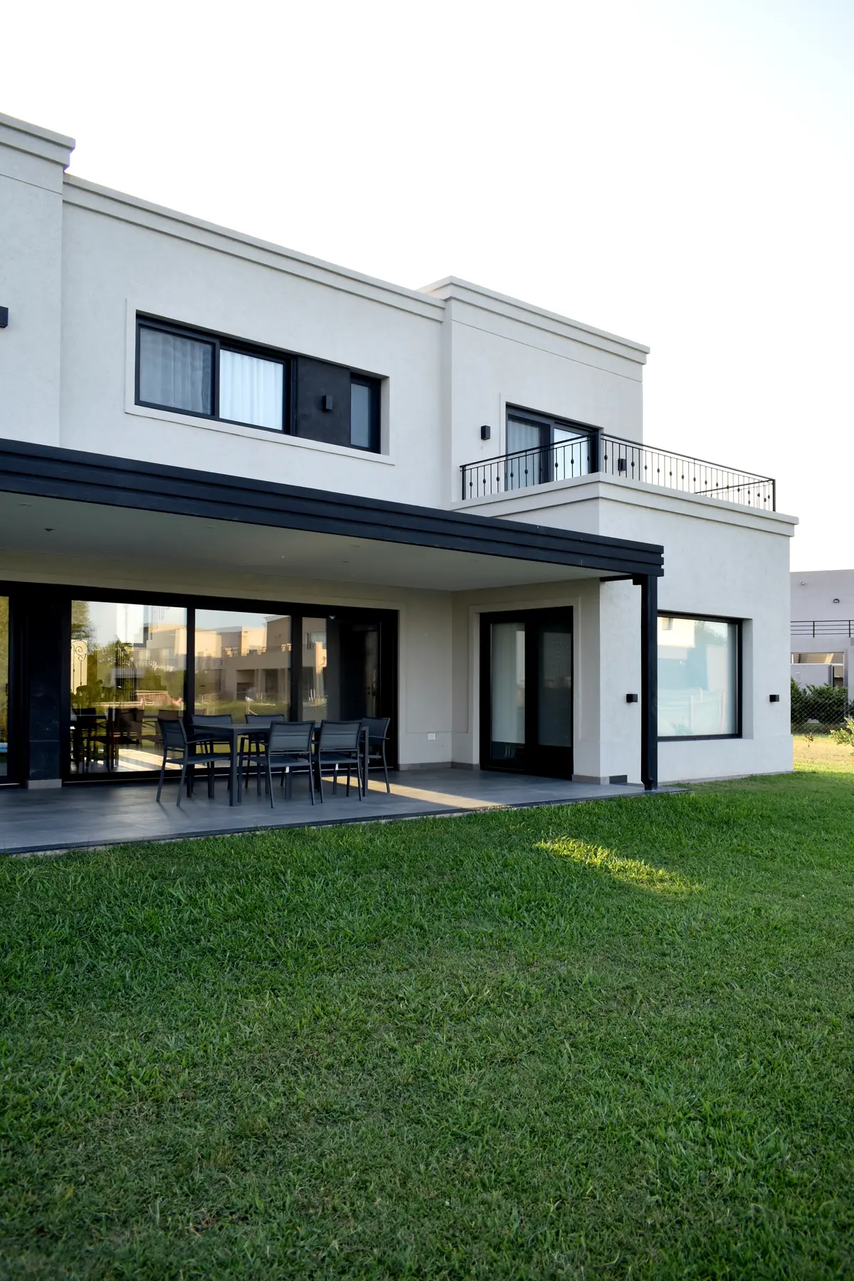 Fachada moderna com pátio, gramado e céu claro — projeto Casa CG191, por EZ architects, em Belén de Escobar