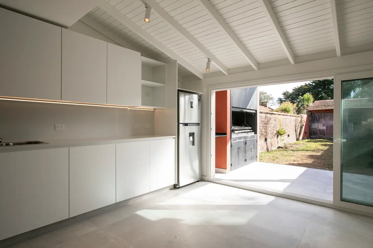 Cozinha moderna minimalista com armários brancos e detalhes em microcimento — projeto Obra Martinez A, por Arq. Lourdes Yarade Saravia, em Martínez
