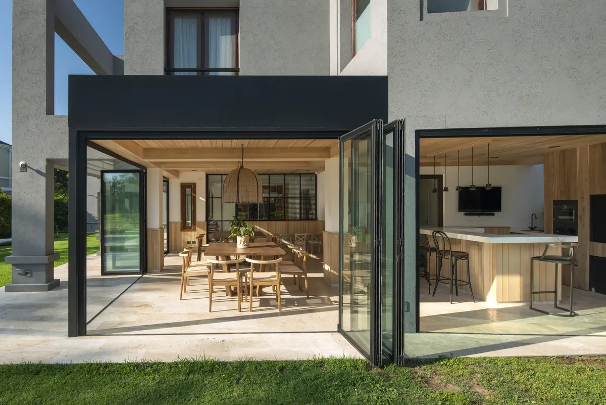Fachada moderna com pérgola e deck, portas de vidro deslizantes, sala de jantar externa — projeto Quincho PG, por Estudio Lak
