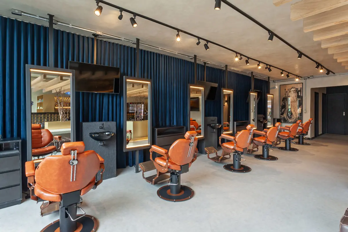 Salón de peluquería moderno con sillones naranjas y pared azul acanalada — proyecto SCHAPER BARBEARIA, por Frederico Bicalho Arquitetura