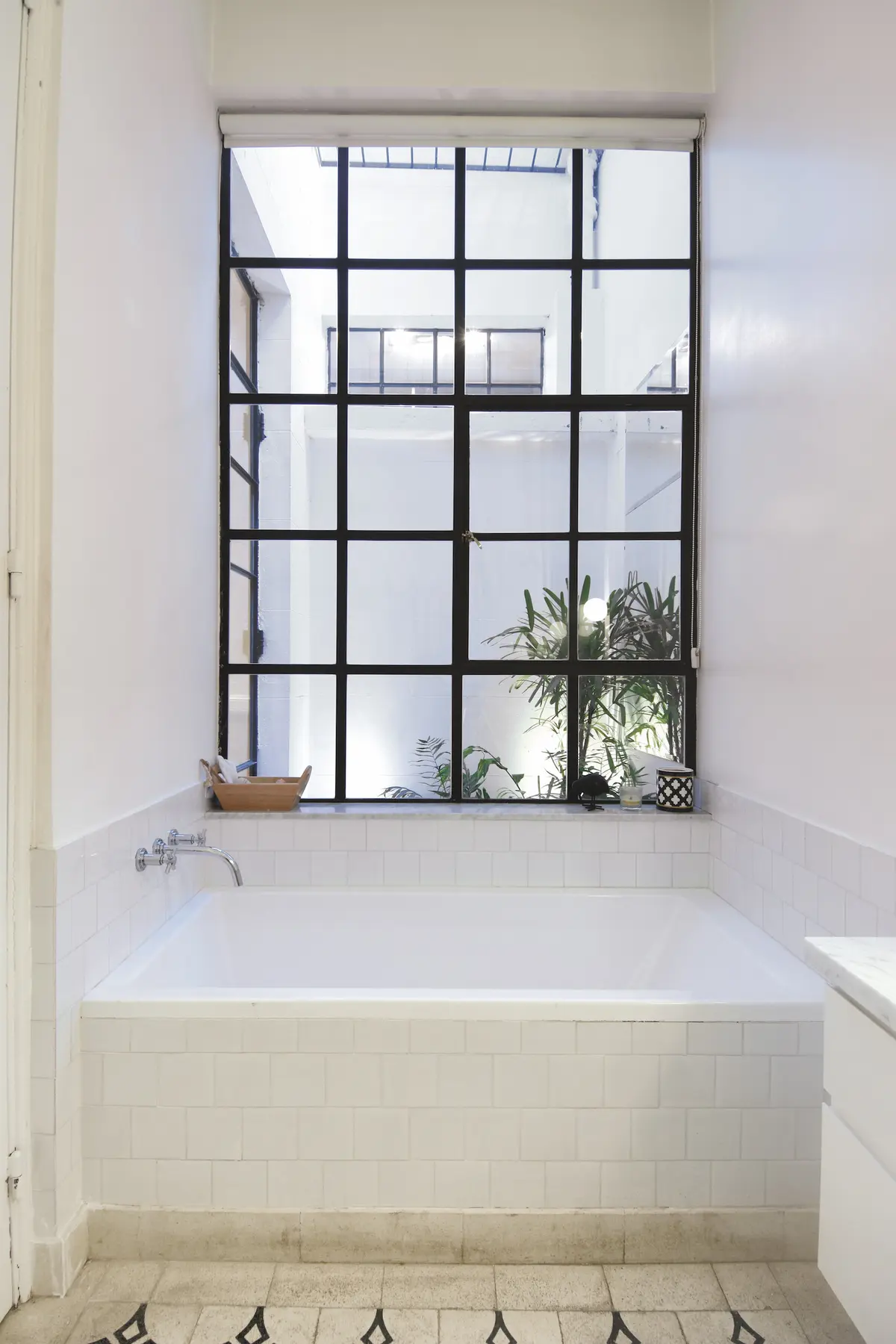Bano minimalista con banera y ventanal negro hacia jardin interior — proyecto Callao, por Estudio Diez Muzzio, en CABA