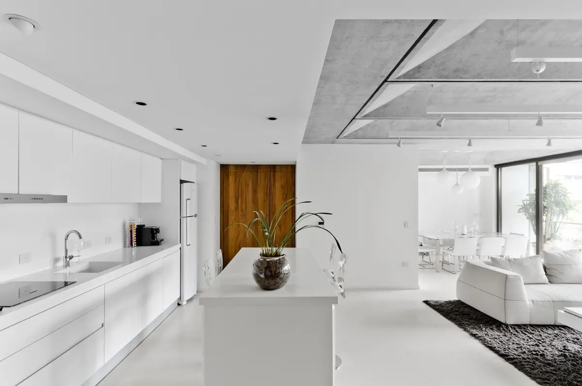 Cocina moderna minimalista con isla blanca y techo de hormigón — proyecto Aleph V, por Claudia Faena Studio, en Puerto Madero