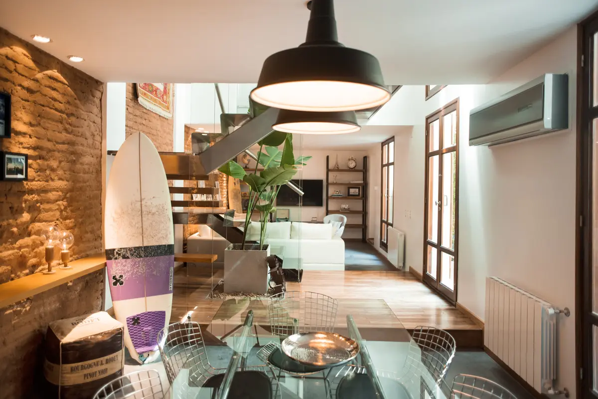 Sala de jantar industrial com tijolos expostos e escada flutuante — projeto Defensa, por Estudio Basa, em CABA