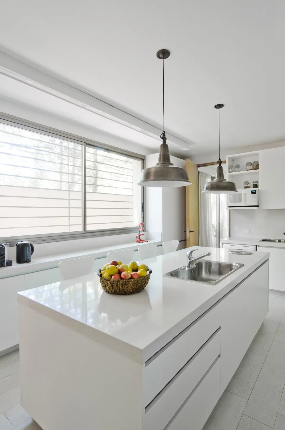 Cocina moderna con isla, luces industriales y grandes ventanales — proyecto Casa P, por Estudio Dado, en San Isidro