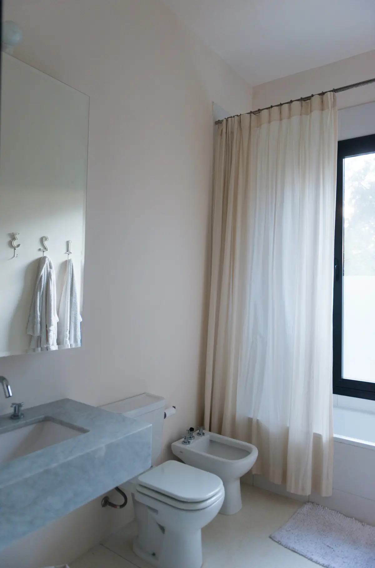 Baño minimalista con cortinas amplias y lavabo integrado — proyecto Casa M, por Estudio Dado, en Pilar