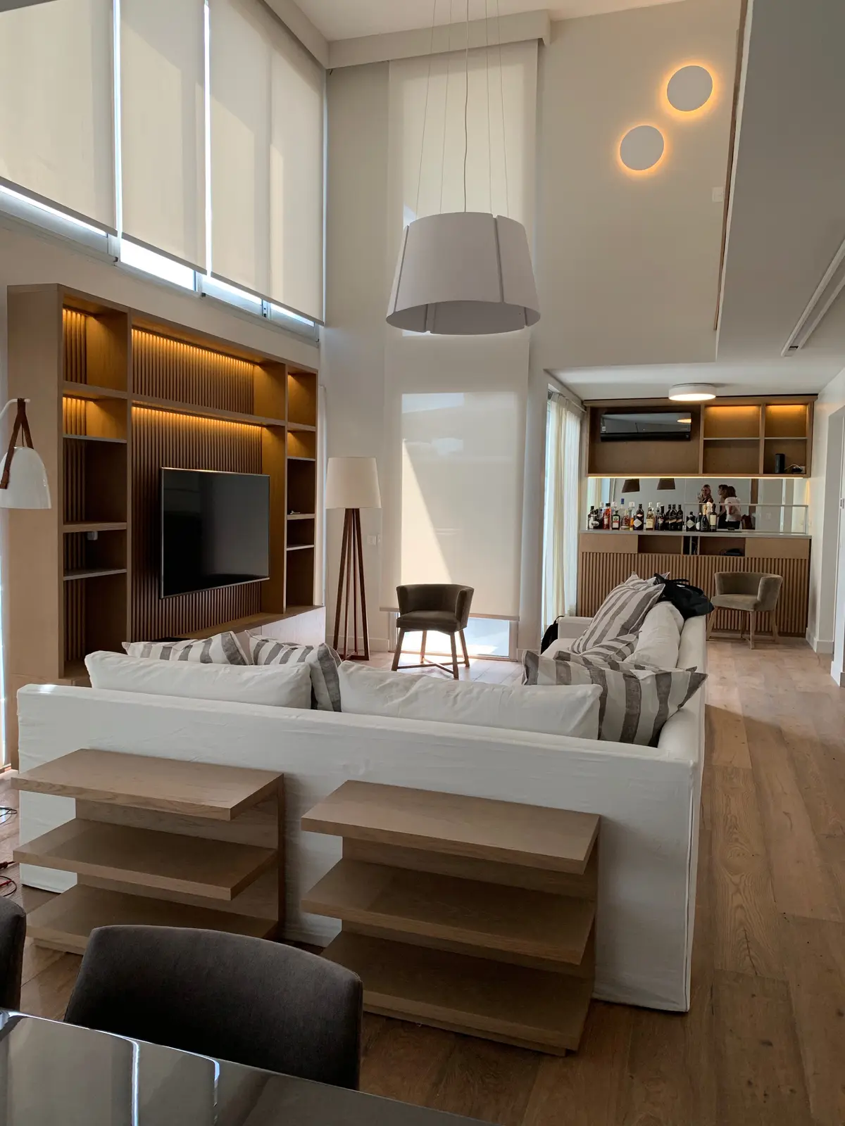 Sala de estar moderna com pé-direito duplo, sofá branco e prateleiras integradas — projeto Piso en Nuñez, por Gutman+Lehrer Arquitectas, em Núñez