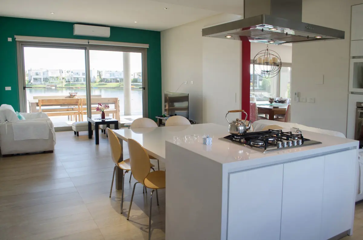 Cozinha moderna aberta com vista para água e ilha branca — projeto Casa Nordelta, por linearecta.arquitectura, em Nordelta