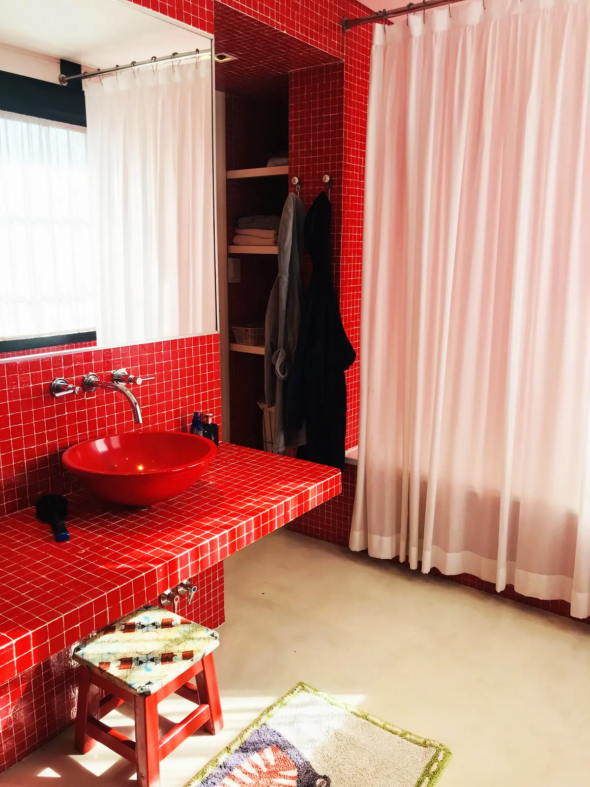 Baño con azulejos rojos, bacha de apoyo y estantes de madera — proyecto Monroe - La Horqueta, por Mgc.arq, en La Horqueta