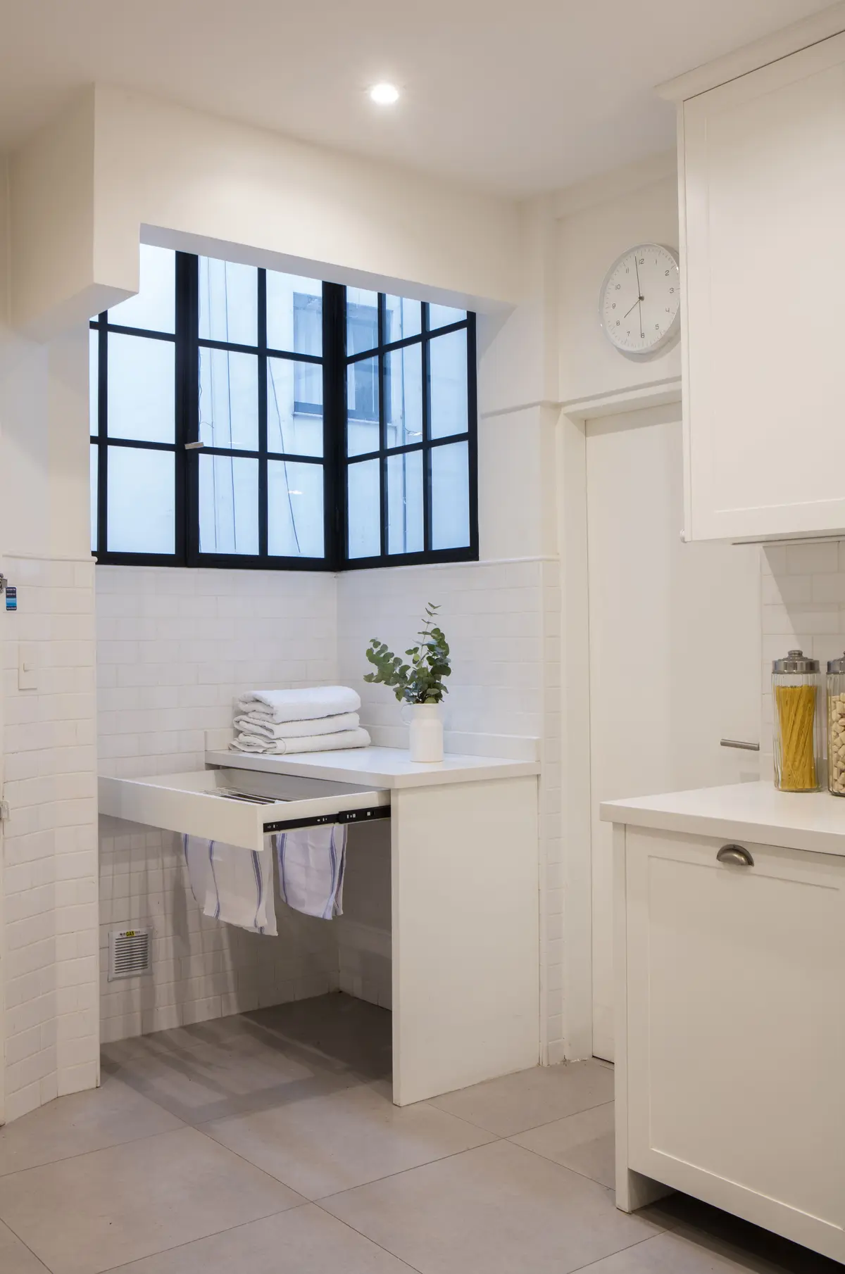 Lavanderia minimalista com janela industrial e prateleiras deslizantes — projeto Juncal, por Parq Estudio, em CABA