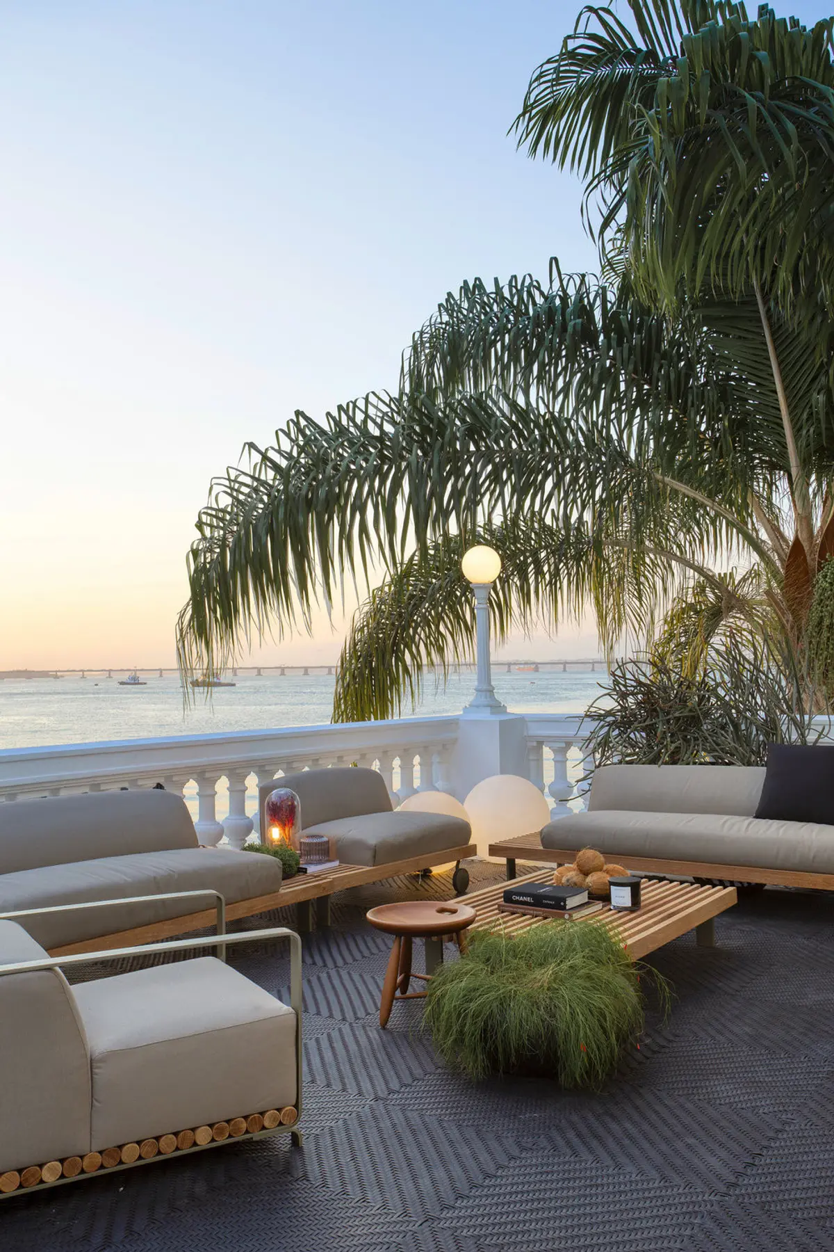 Terraza frente al mar con sofás blancos y palmeras al atardecer — proyecto Casa COR 2019, por Studio Ro-ca