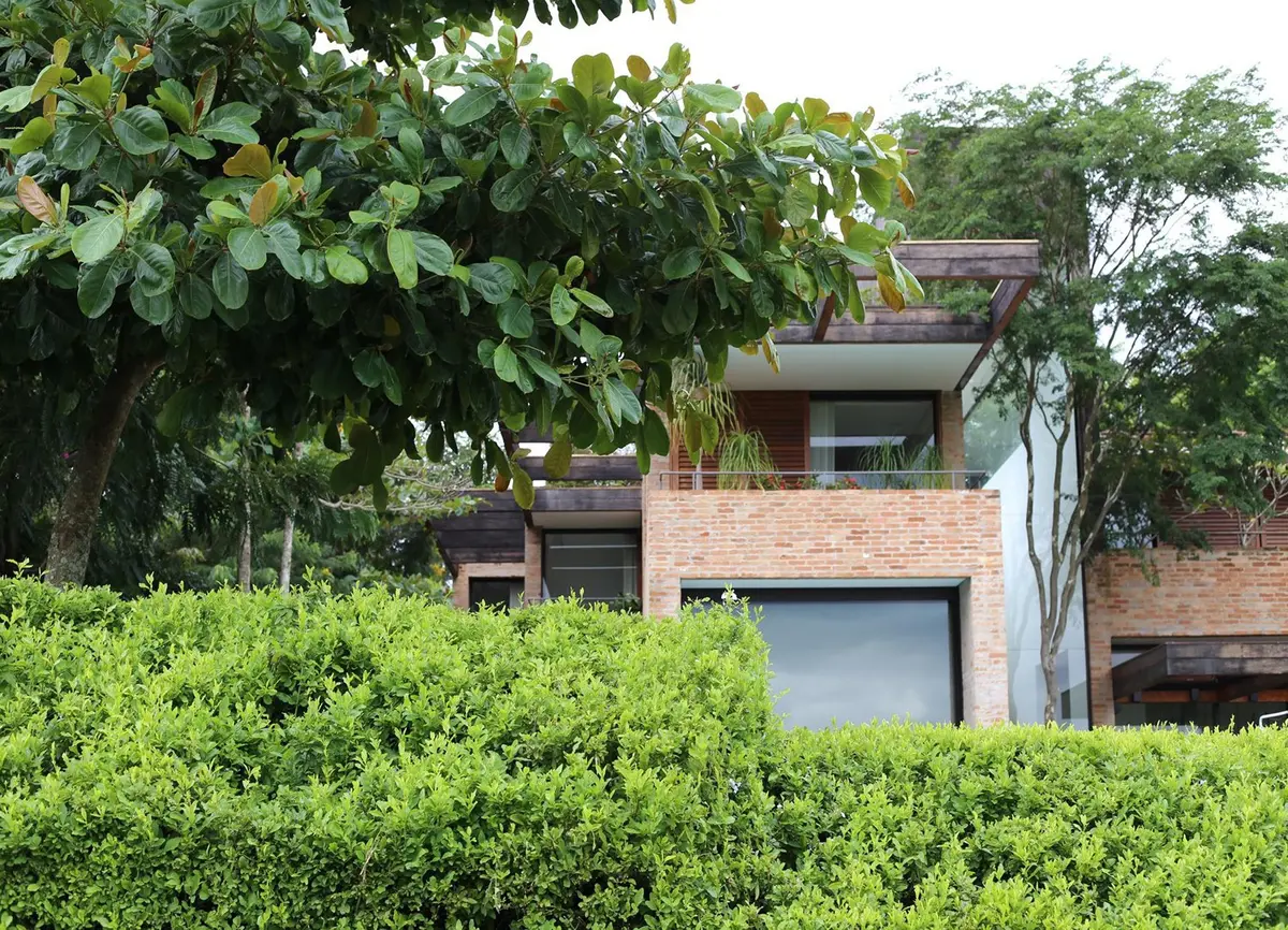 Casa moderna de ladrillo con frente abierto rodeada de vegetación — proyecto Residência MP, por Gil Fialho
