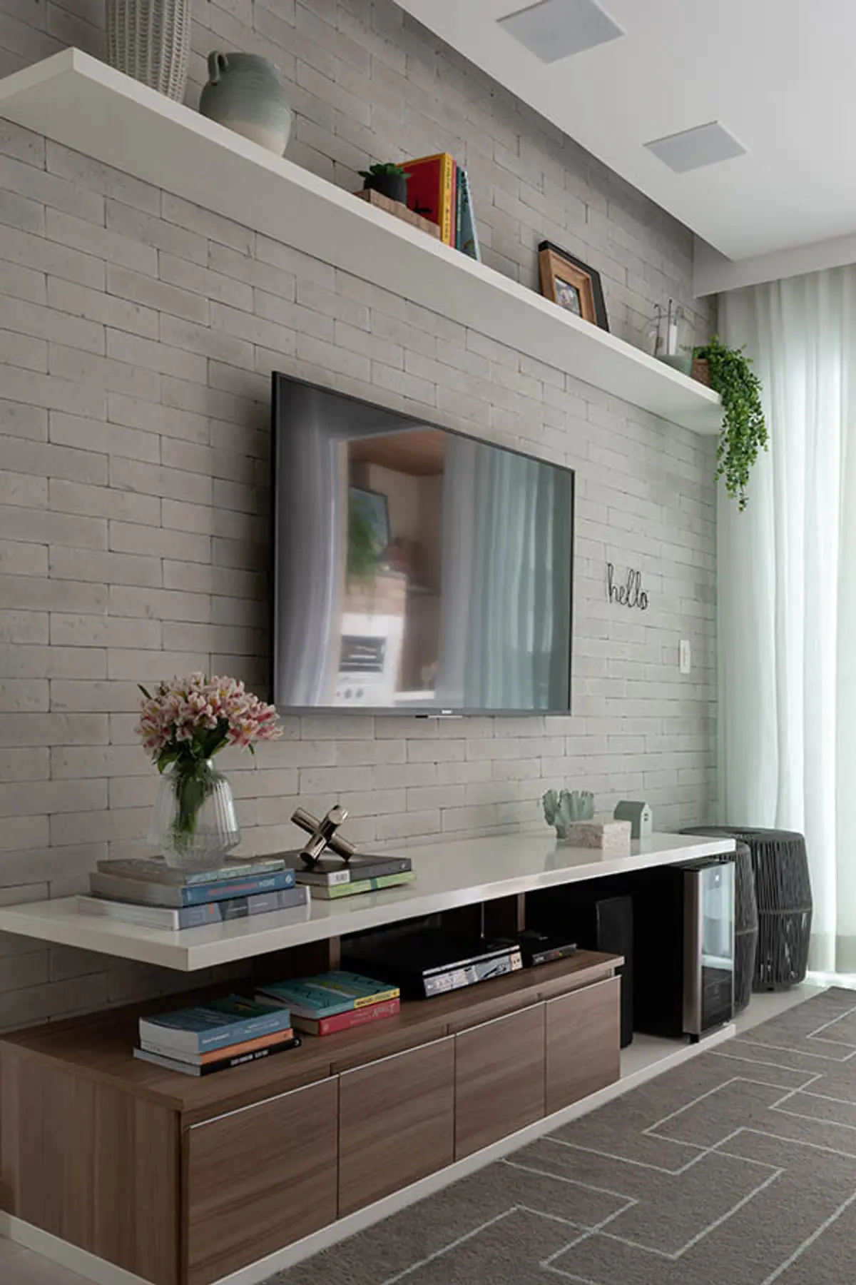 Living moderno con TV mural, mueble de madera y pared de ladrillo blanco — proyecto Apartamento Nóbrega, por Amanda Miranda