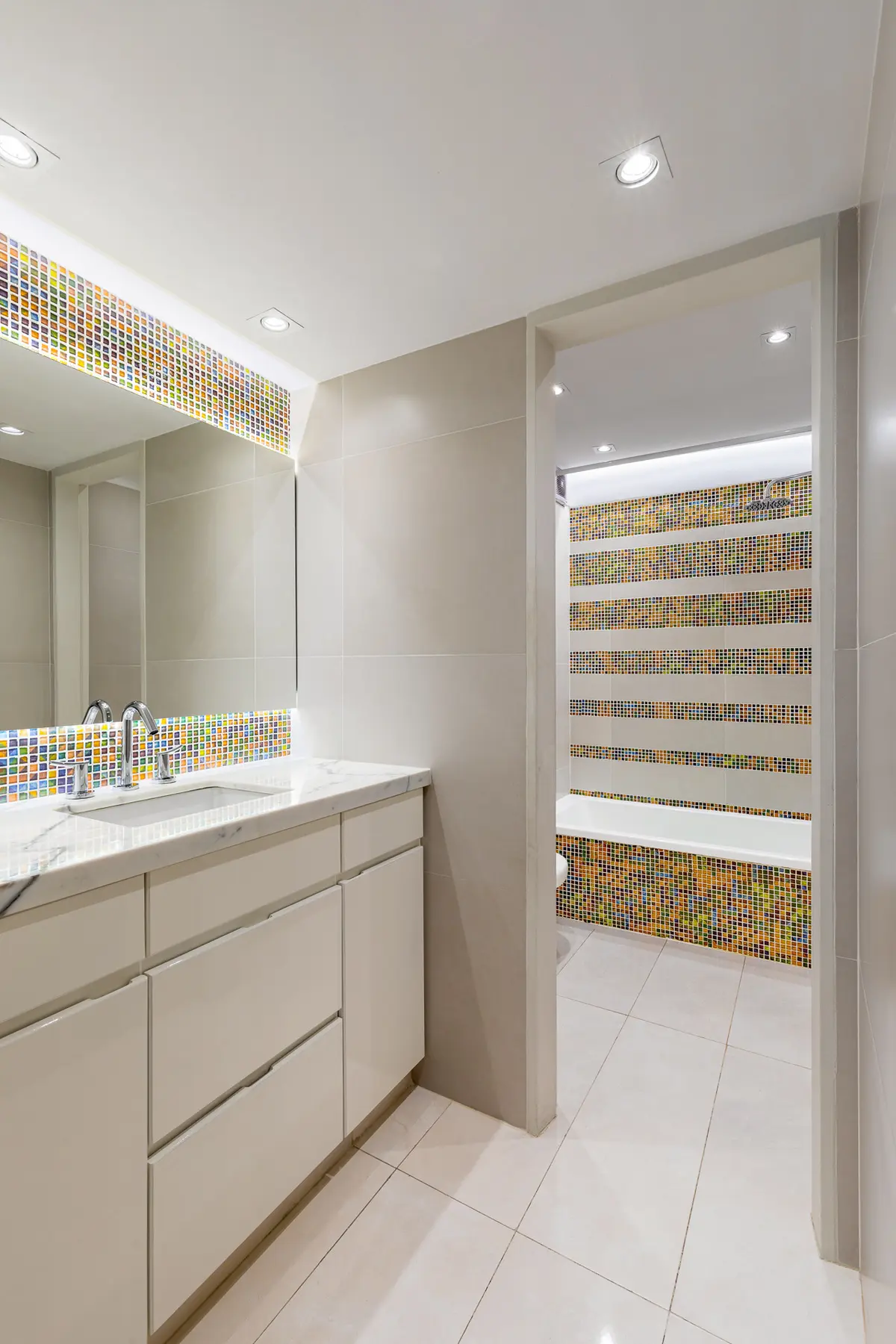 Banheiro moderno com bancada branca, mosaicos coloridos e banheira embutida — projeto Baño en Belgrano, por MARCO GUOLI PHOTO, em Belgrano