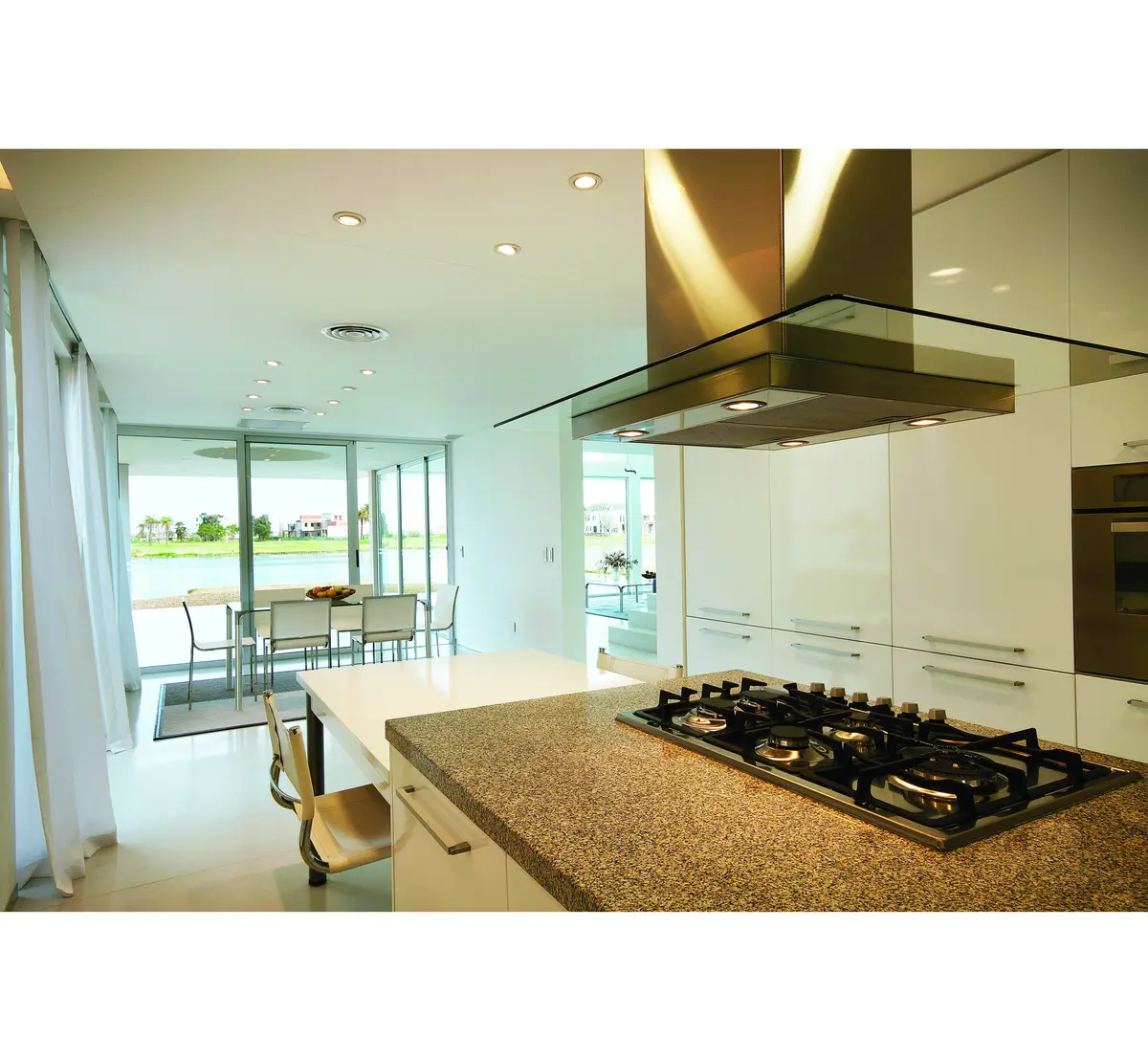 Cozinha e sala de jantar modernas em plano aberto com ilha e janelas grandes — projeto Casa Pool, por Vanguarda Arquitectos, em Nordelta