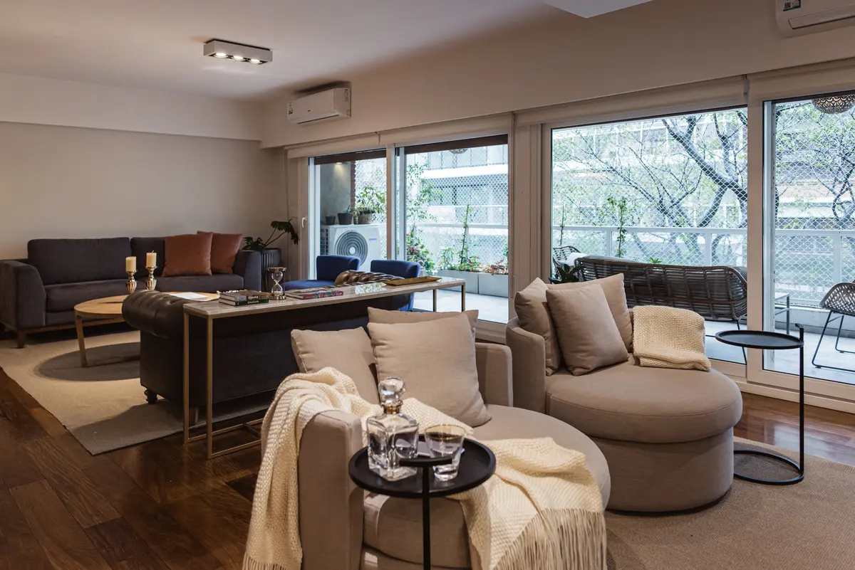 Sala de estar moderna com janelas amplas, poltronas curvas e luz quente — projeto PROYECTO CABA, por HALESA ESTUDIO, em Belgrano