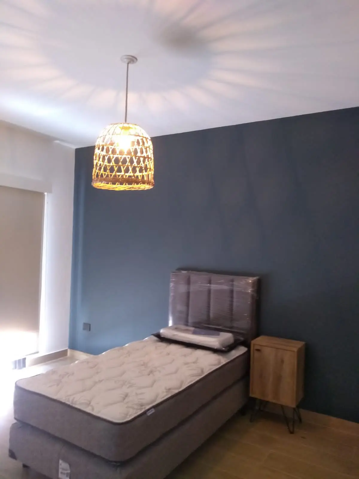 dormitorio minimalista con cama single y lámpara de mimbre — proyecto Siete soles, por Design & Living, en Córdoba