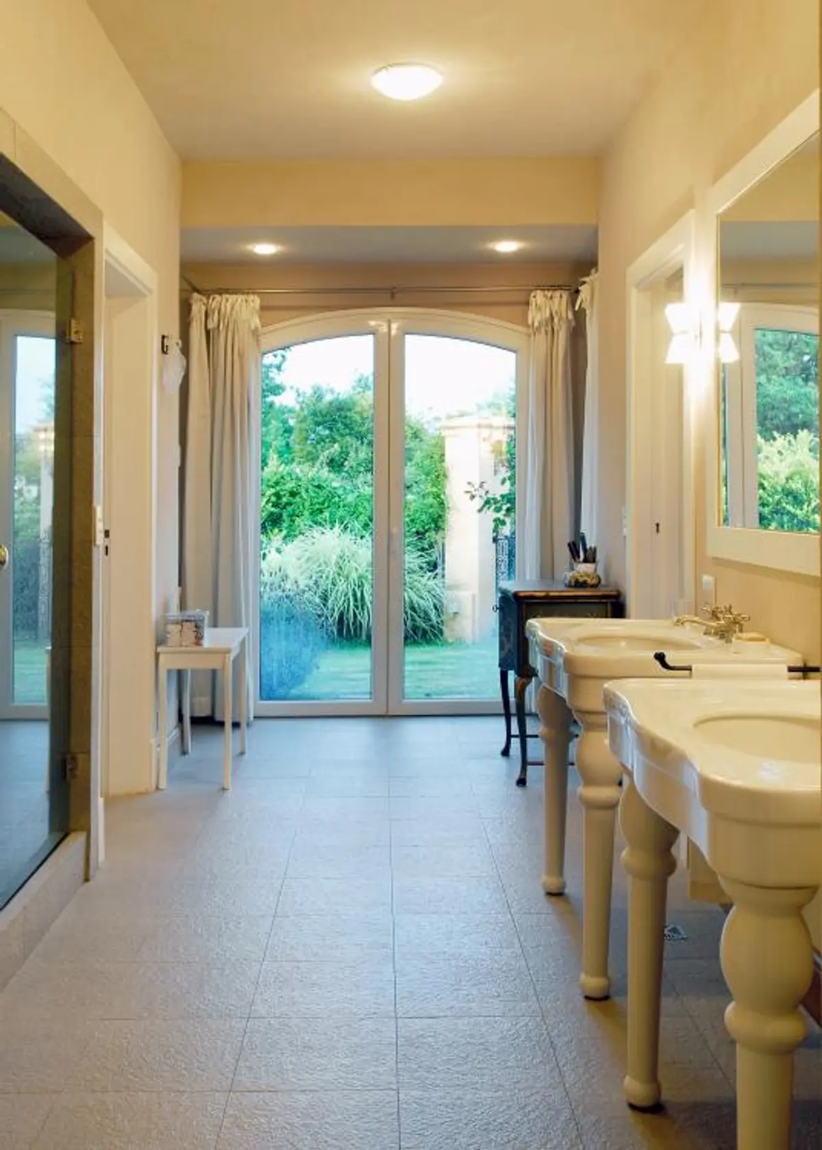 Baño amplio con puertas arqueadas al jardín y lavabos dobles — proyecto Casa PV, por Estudio Junor, en Pilar