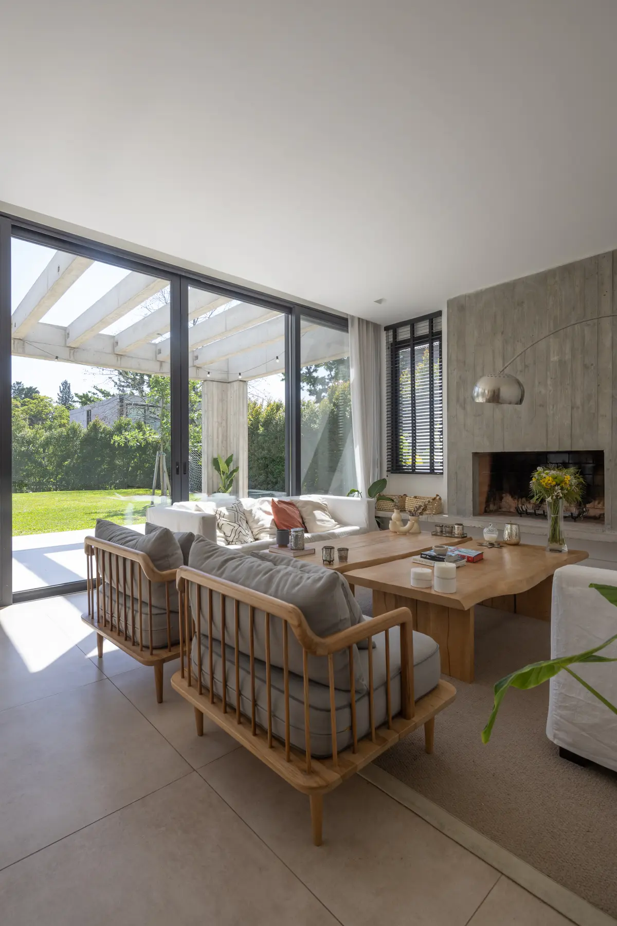 Sala de estar moderna com janelas do chão ao teto, lareira de concreto e mesa de madeira — projeto CASA RuZa, por Alfredo Orfila arquitectura, em Benavidez
