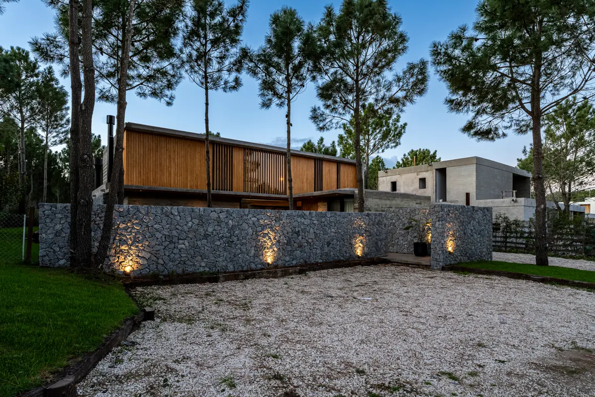 Fachada moderna de pedra e madeira com iluminação integrada — projeto casa la huella, por Guerrero Arquitectos, em Pinamar