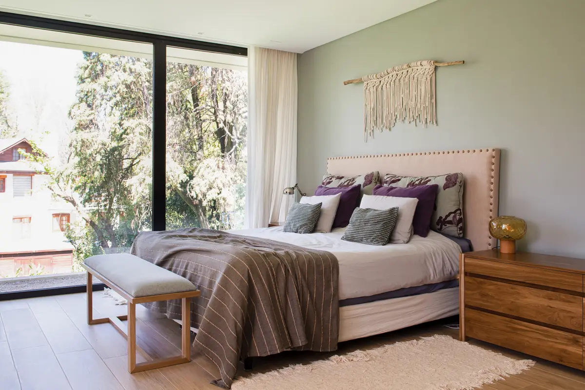 Dormitorio luminoso con vista al bosque y detalles boho — proyecto Casa Highland Park, por C - ESTUDIO, en Pilar