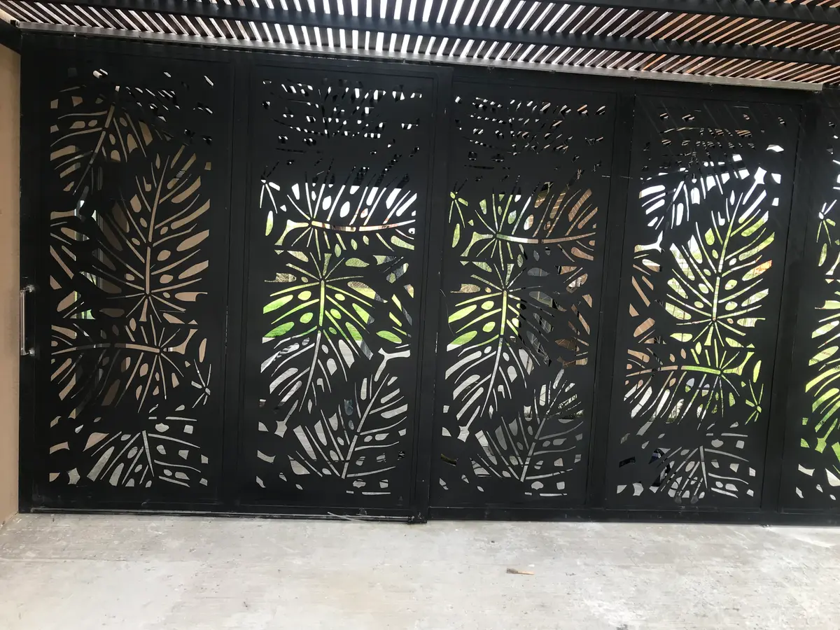 fachada moderna com portão de metal vazado e vegetação — projeto Chapa calada decorativa, tríptico árbol de la vida oara portones corredizos y ce, por Pintastic, em Belén de Escoba