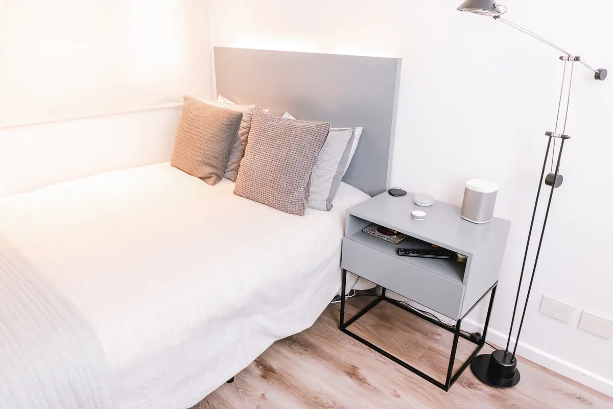 Dormitorio minimalista con cama blanca, mesita de noche moderna y piso de madera — proyecto Cabrera, por Tali Estudio, en Palermo
