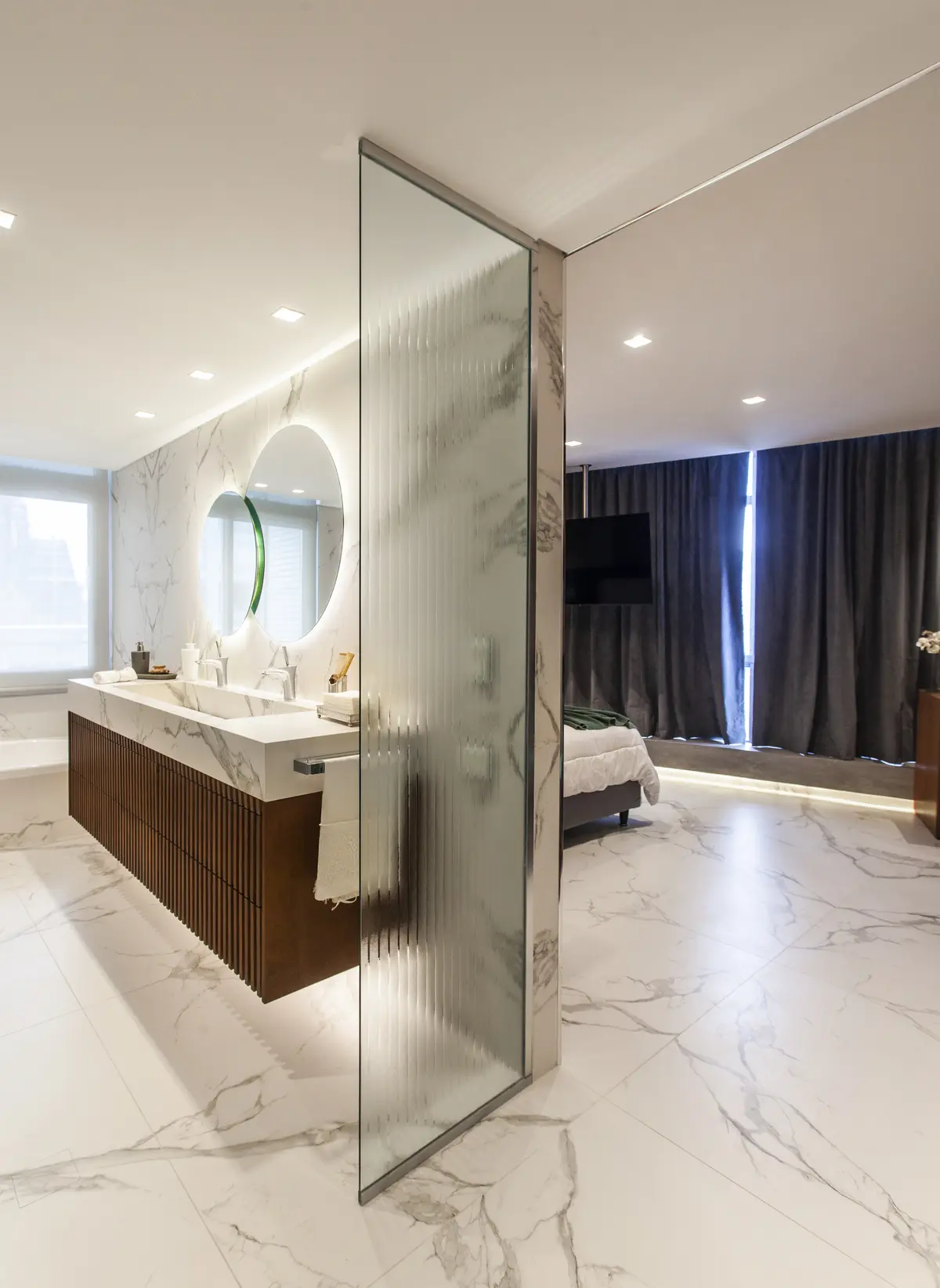 Baño de lujo abierto a dormitorio, con mampara de cristal y mármol — proyecto Pacífico BRT, por Vanguarda Arquitectos, en CABA