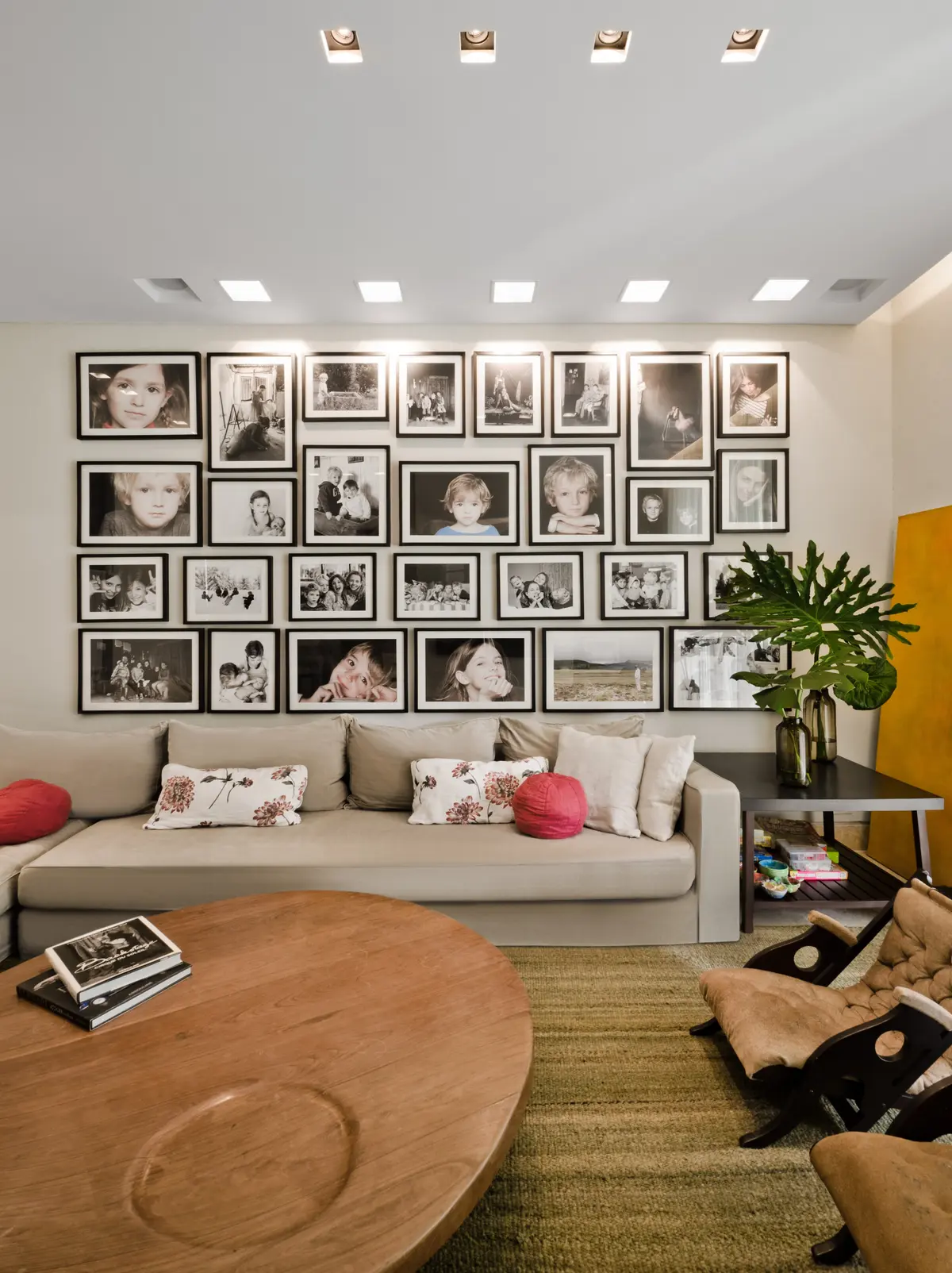 Sala de estar moderna com sofá seccional, parede de fotos e mesa de madeira — projeto Casa H, por Estudio Dado, em Belgrano