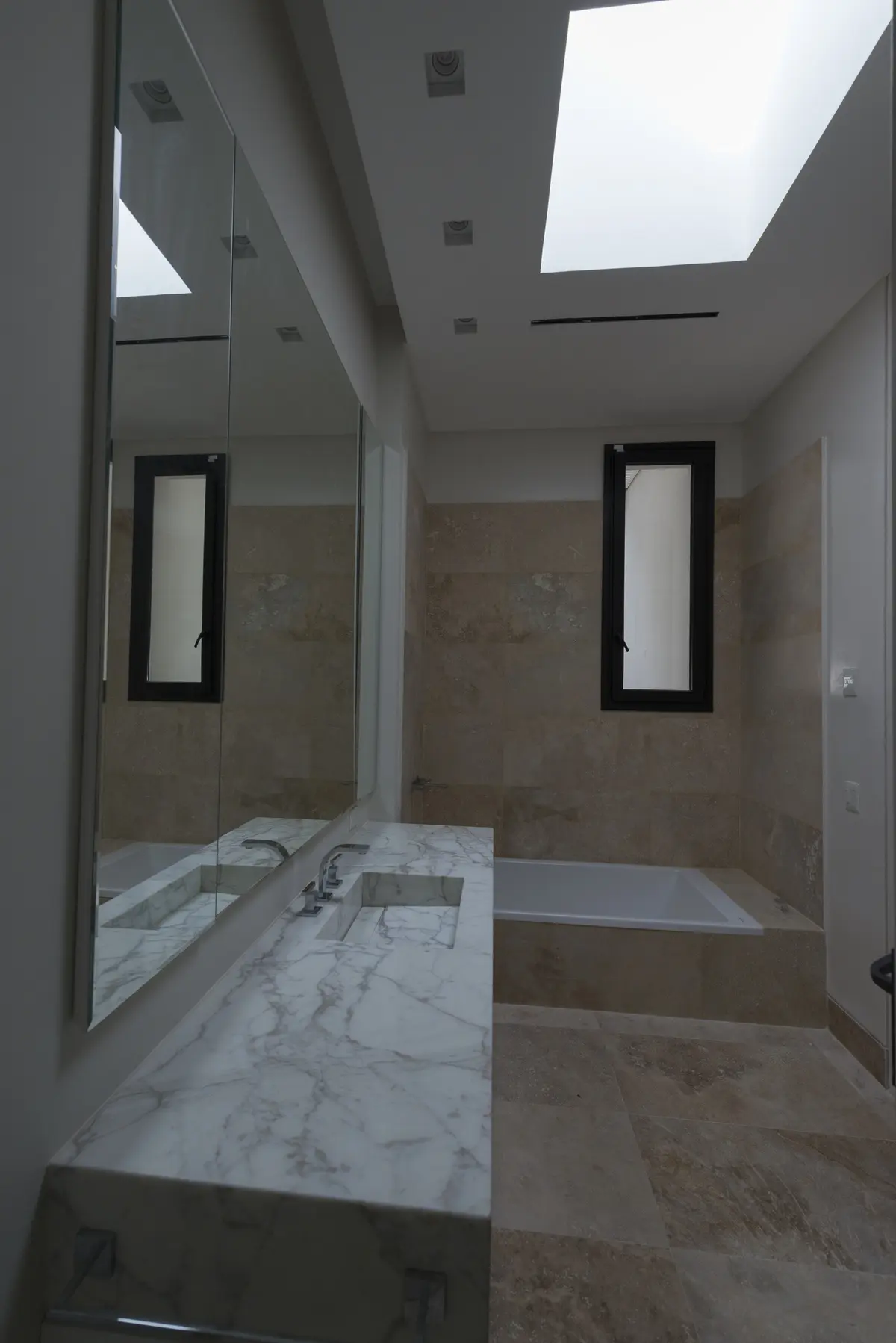 Baño moderno con mesada de mármol, bañera y claraboya — proyecto Casa C, por Estudio Dado, en Belgrano
