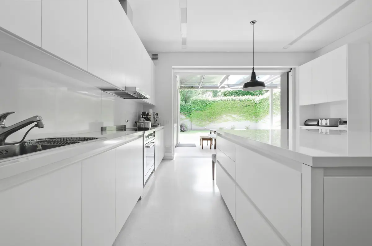 Cozinha moderna branca minimalista com ilha e vista para o jardim — projeto Casa D, por Estudio Dado, em Belgrano
