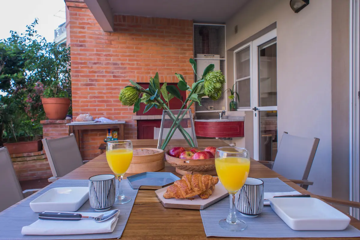 Comedor exterior con mesa de madera y ladrillos a la vista — proyecto Casa en Nordelta, por Gutman+Lehrer Arquitectas, en Nordelta