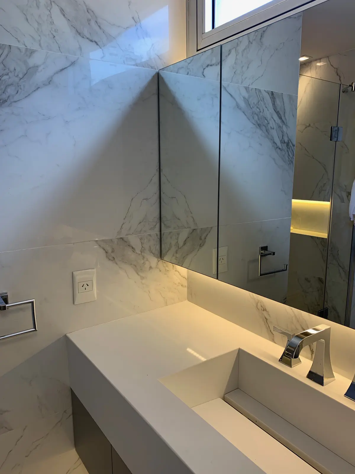Banheiro moderno com revestimento de mármore, pia integrada e torneira angular — projeto Piso en Nuñez, por Gutman+Lehrer Arquitectas, em Núñez