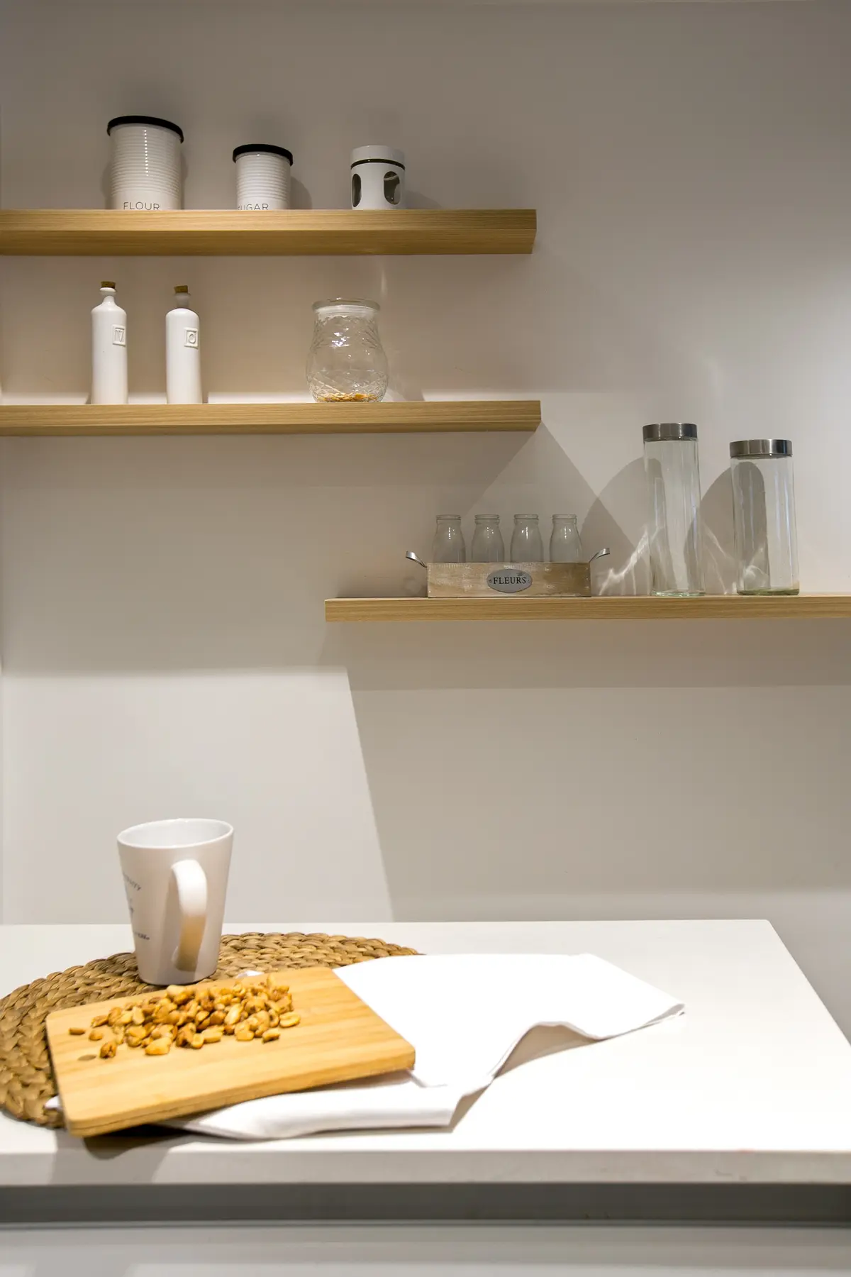 Cocina con estantes flotantes de madera y objetos blancos y de vidrio — proyecto Callao, por Mgc.arq, en CABA
