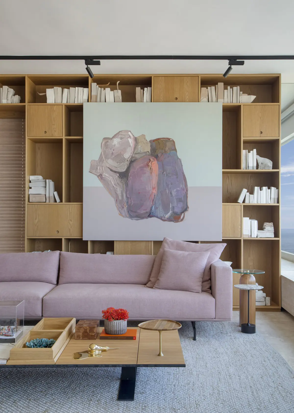 Living moderno con sofa rosa, estanterias madera y cuadro abstracto — proyecto PS House, por Studio Ro-ca