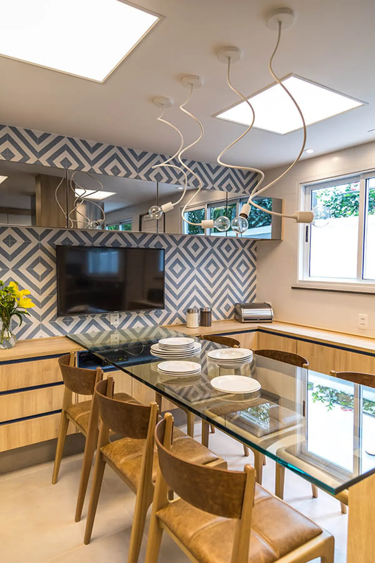 Comedor moderno con mesa de vidrio y cocina integrada con azulejos geométricos — proyecto Casa Barra ED, por Amanda Miranda