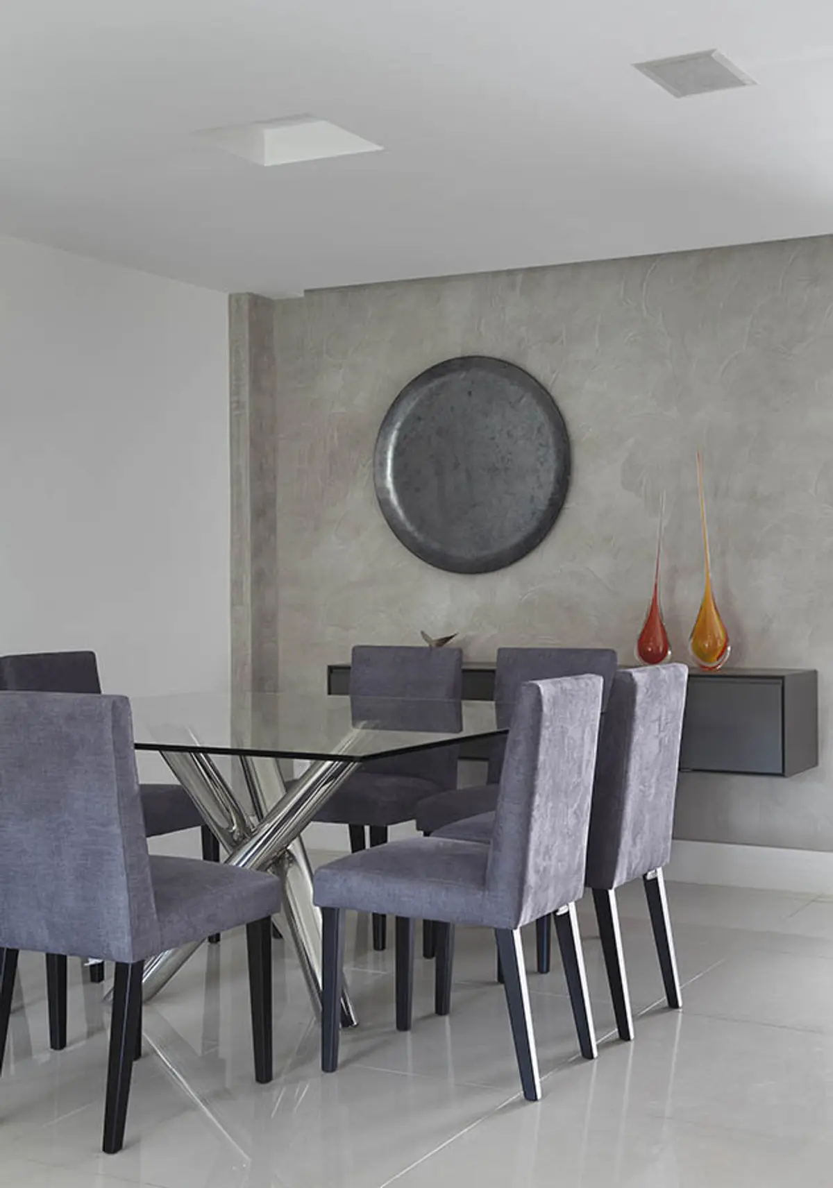 Comedor contemporáneo con mesa vidrio, sillas grises, pared hormigón visto — proyecto Casa Barra ED, por Amanda Miranda
