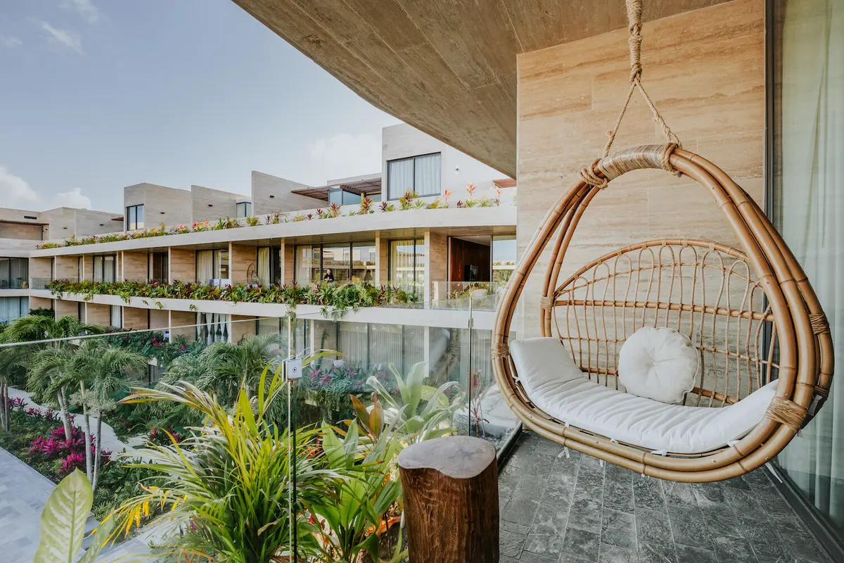 Balcón moderno con silla colgante de ratán y vista costera — proyecto Contemporary Modern Living, por Interiors Tulum