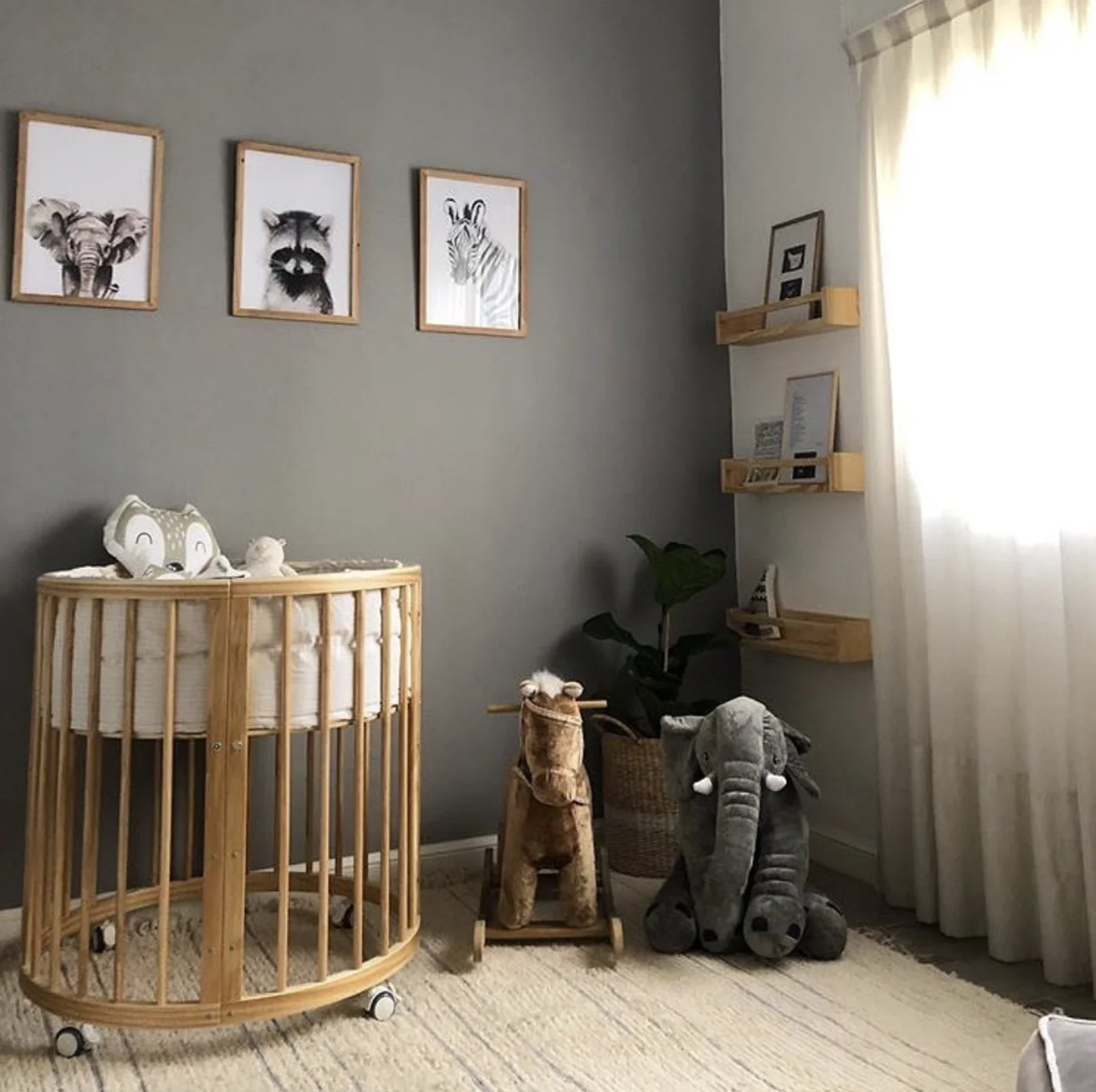 Habitación infantil con arte de animales y cuna redonda de madera.