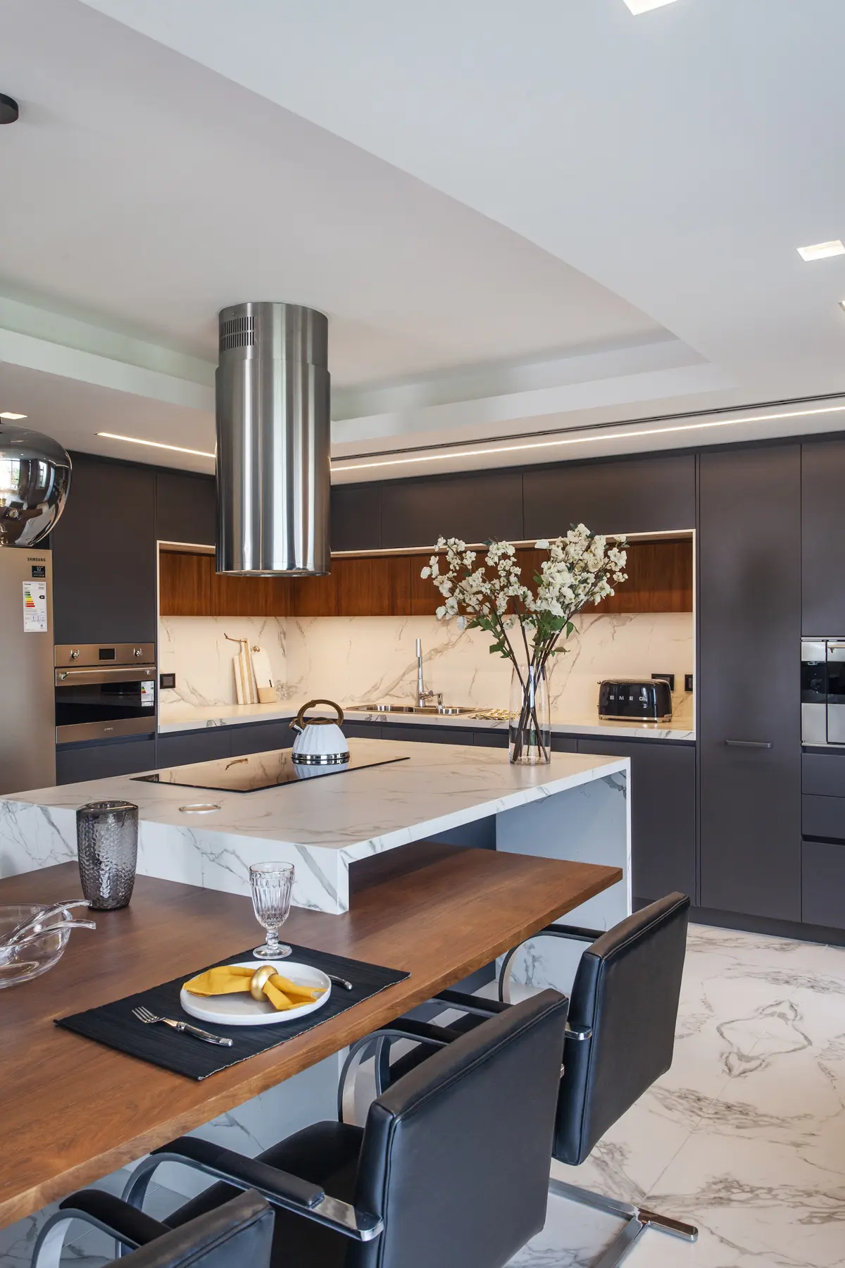Cocina moderna con isla de mármol y comedor integrado, iluminación indirecta — proyecto Pacífico BRT, por Vanguarda Arquitectos, en CABA